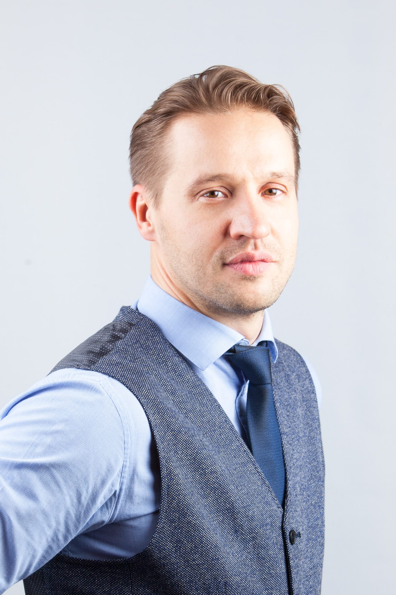 Giedriaus Žiogo portretas su mėlynais marškiniais, pilka liemene ir kaklaraiščiu